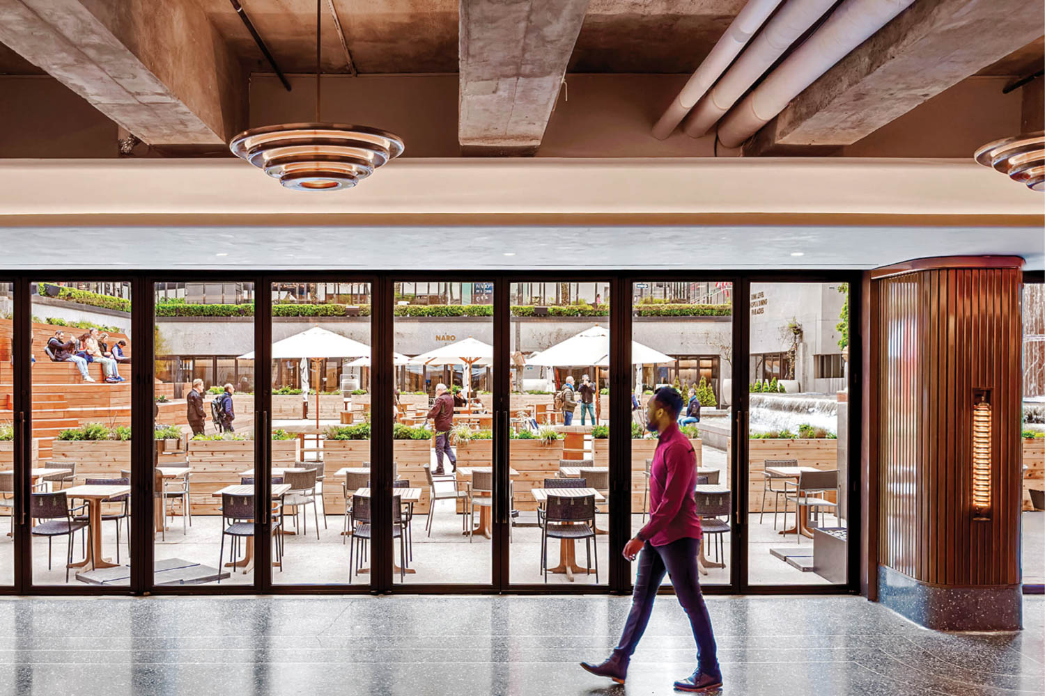 person walking down hallway with views to the outdoor dining area