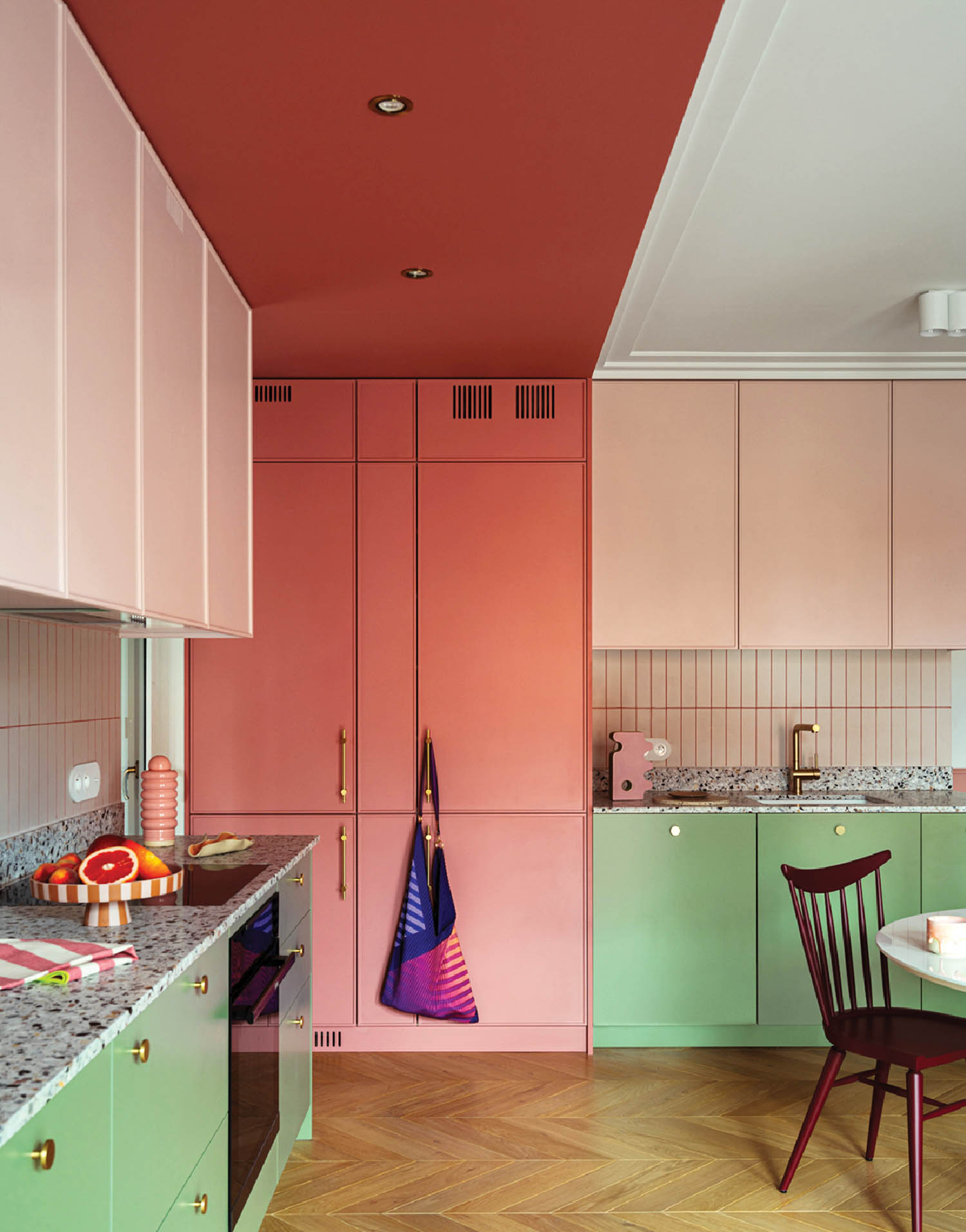 kitchen with pastel pink and green cabinets and wooden parquet flooring