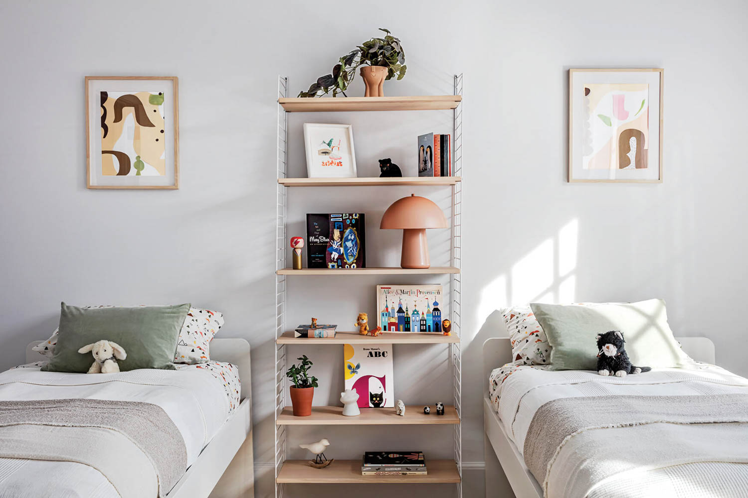 children's bedroom with two beds, funky artwork and shelf in between