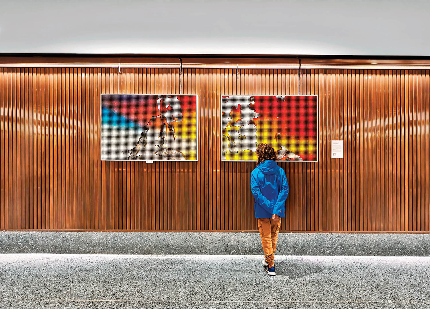 person looking at artwork hanging on wooden paneled walls