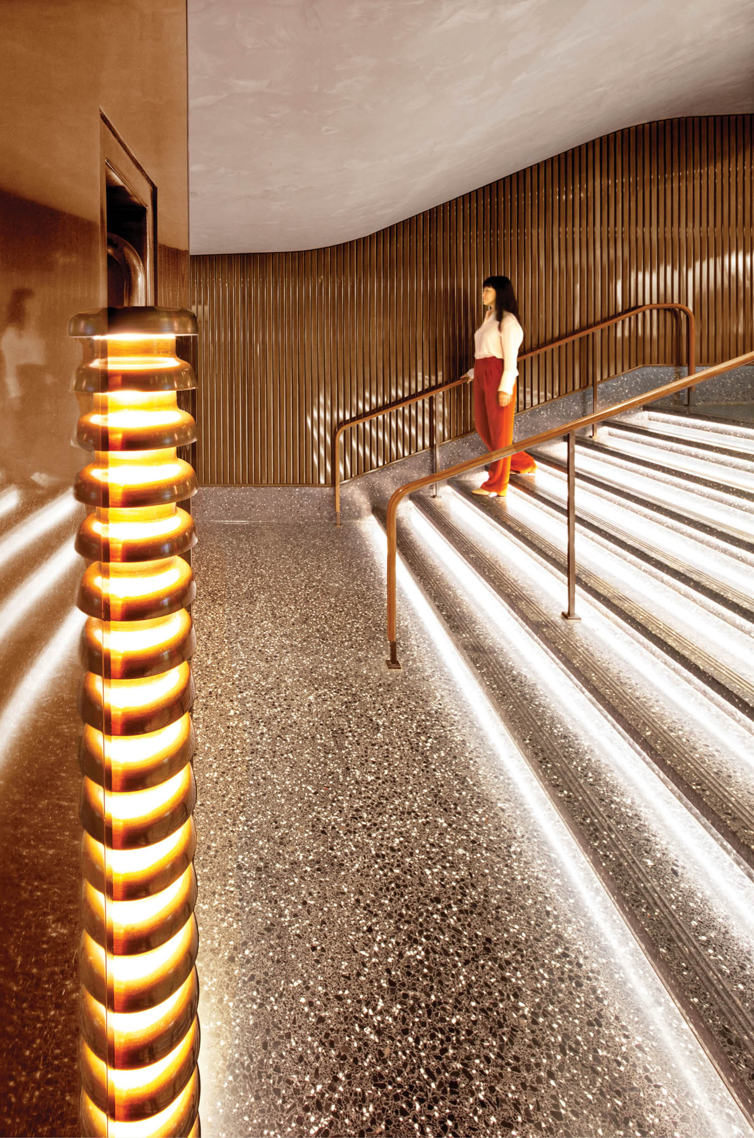 closeup of bronze sconces and stairs that are lit up