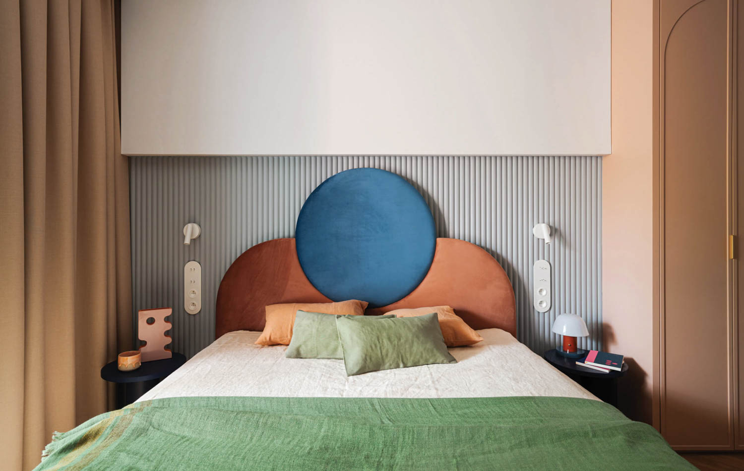 bedroom with round blue headboard, green and white sheets and brown drapes