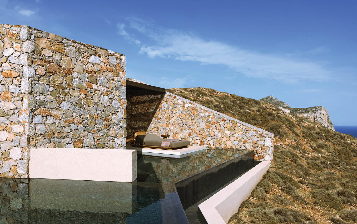 a stone wall next to a pool