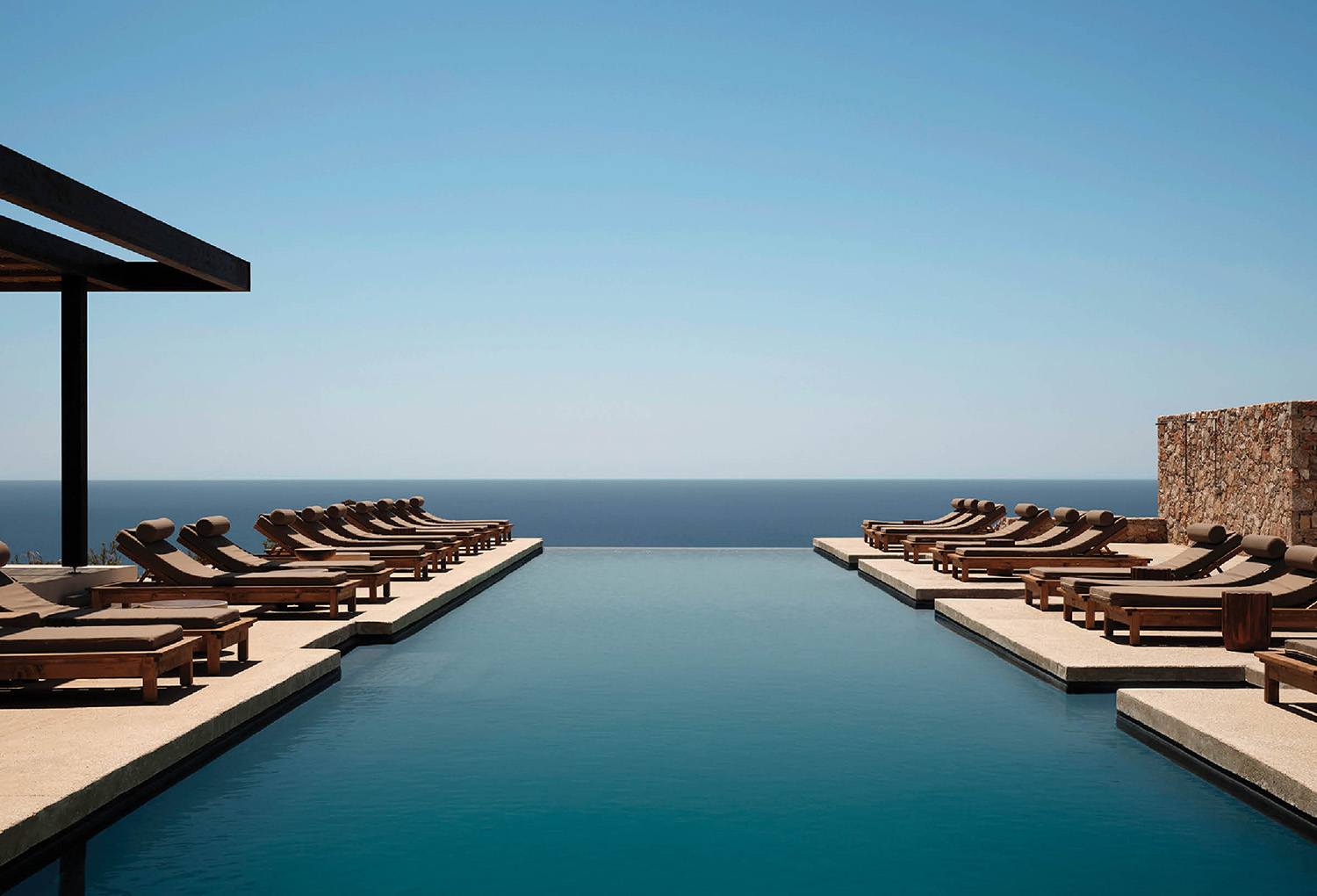 a long pool with lounge chairs and a view of the ocean