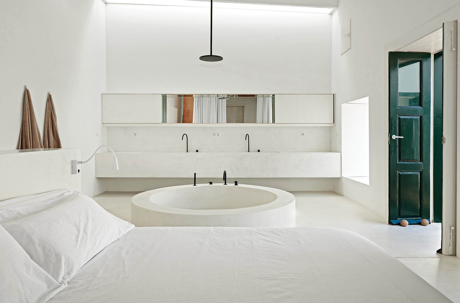 a white bedroom with a large bed and a large mirror