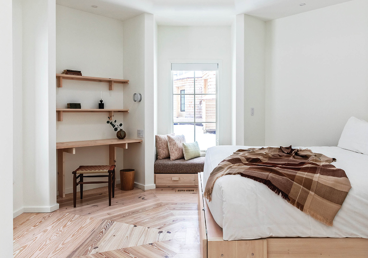 A bedroom with a bed, desk and shelves