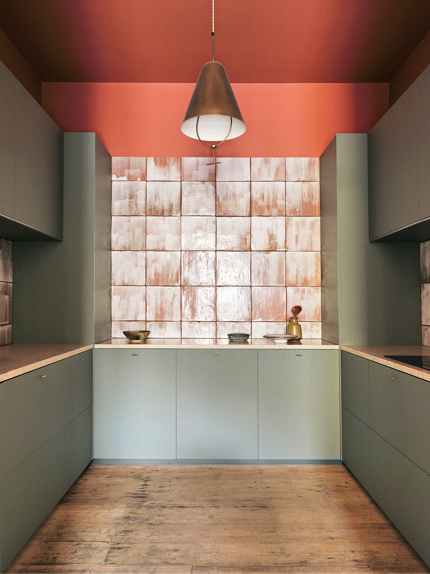 A kitchen with a red wall and a white tiled wall