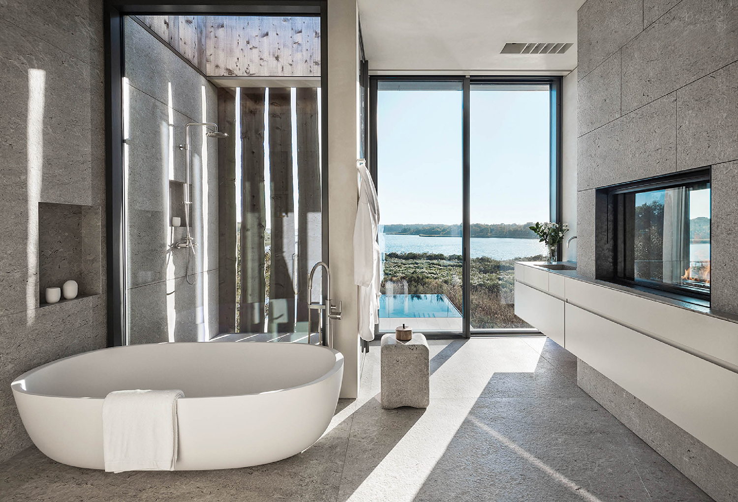 bathroom with large white freestanding tub, glass shower and view to the outdoors