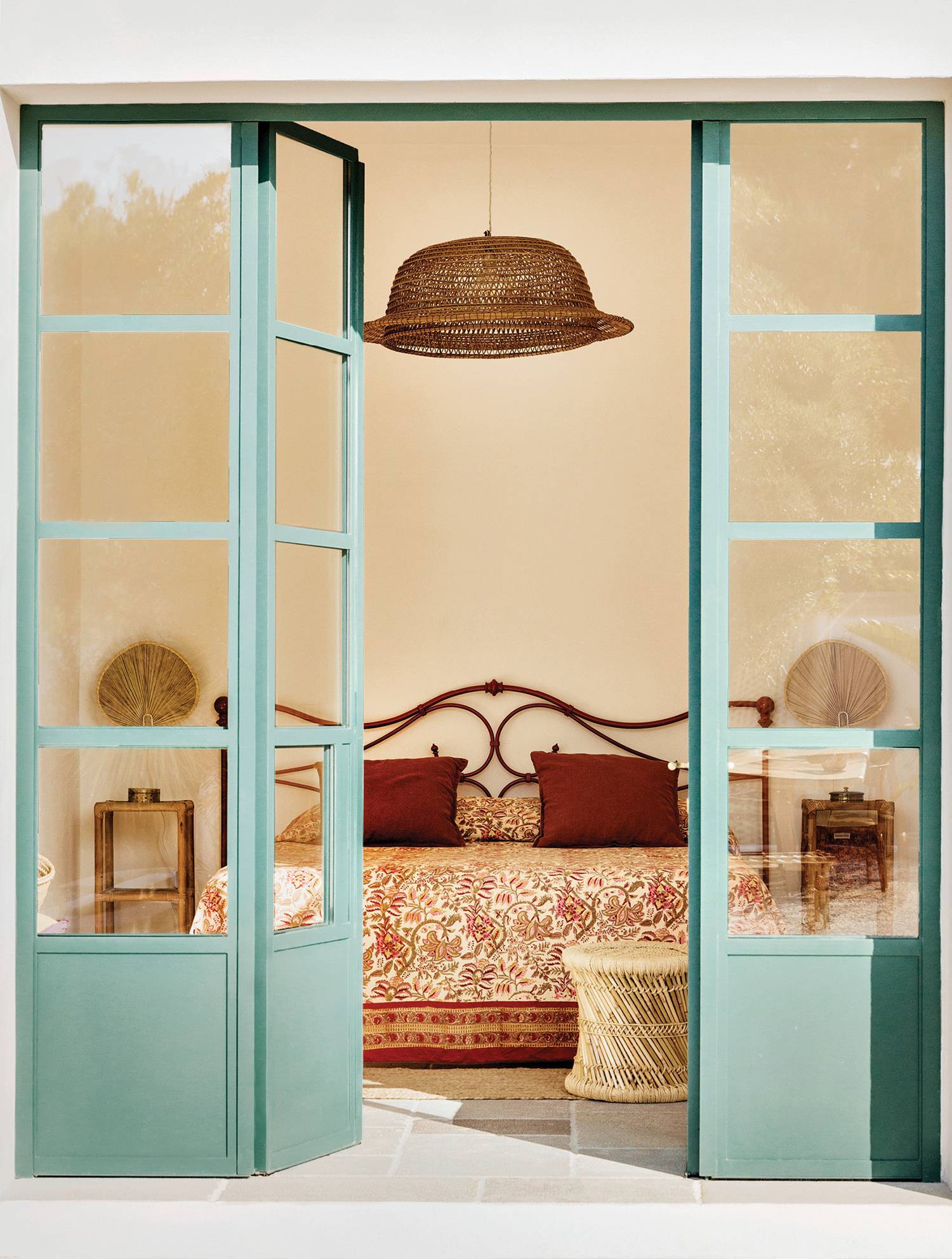 pastel green french doors open to a bedroom with maroon pillows and bedsheet