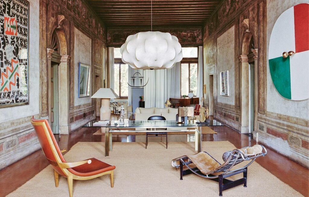 office space with white chandelier, intricate walls, round Italian flag mirror and seating