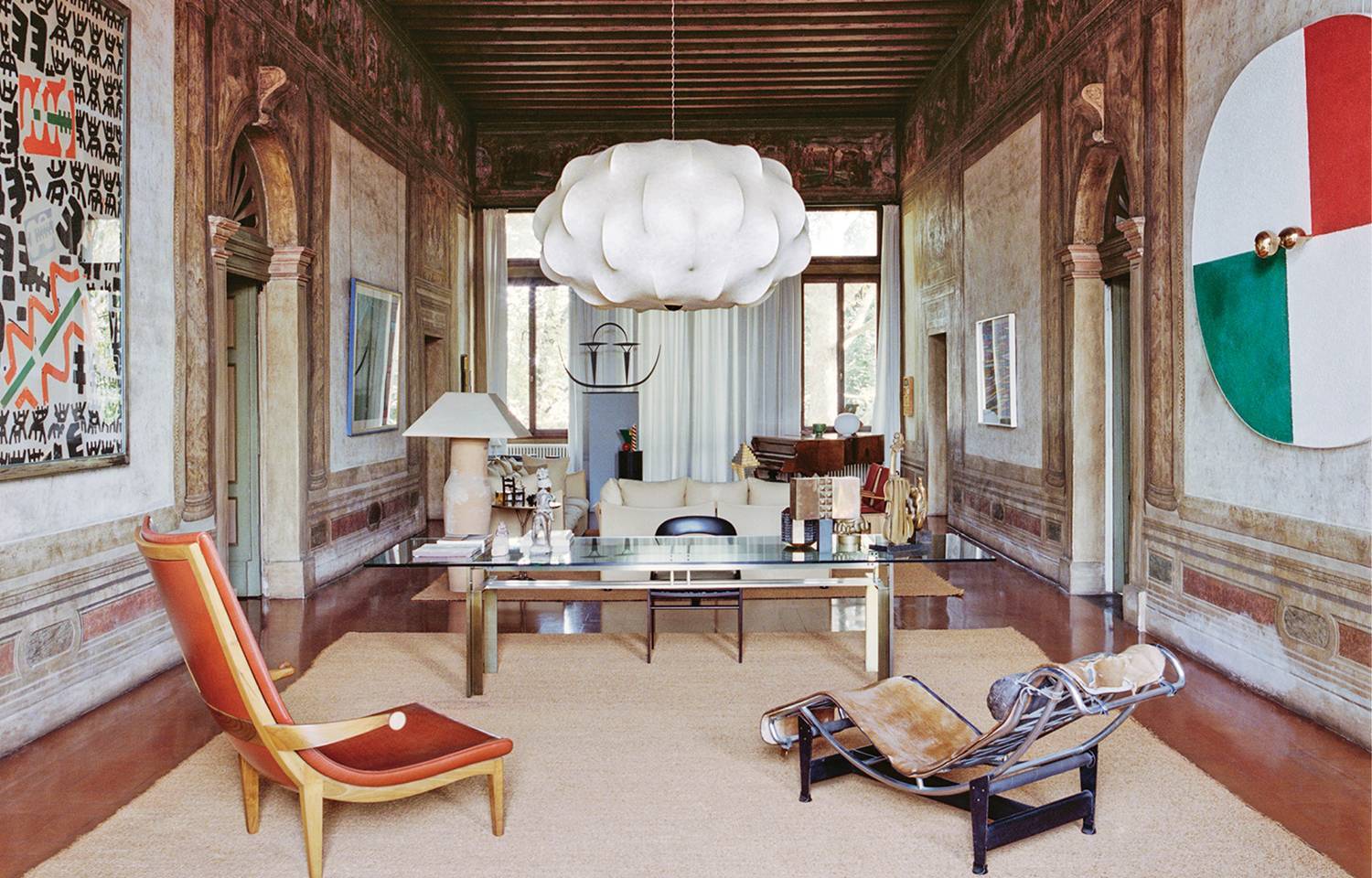 office space with white chandelier, intricate walls, round Italian flag mirror and seating