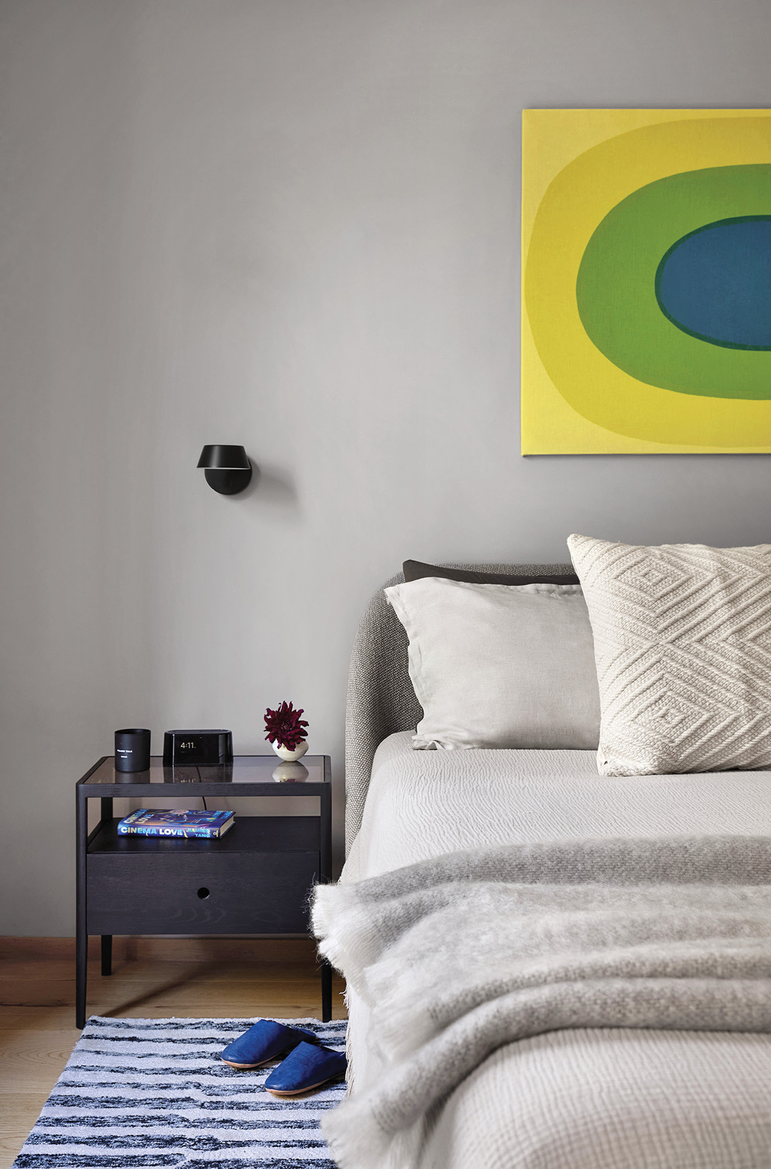 "A bedroom with a bed, a nightstand, and a painting"