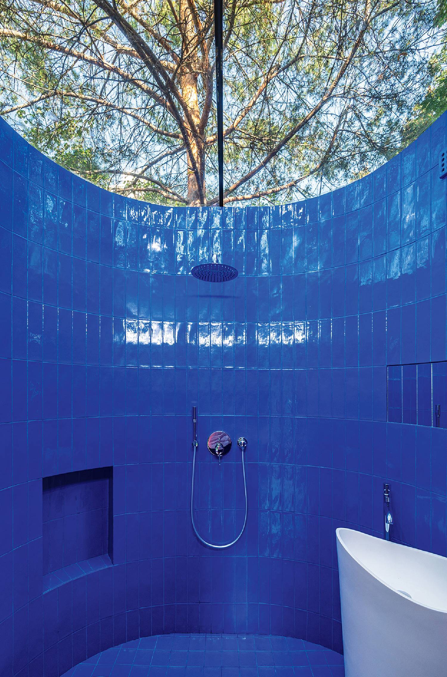 outdoor bathroom with tub and blue tile all around