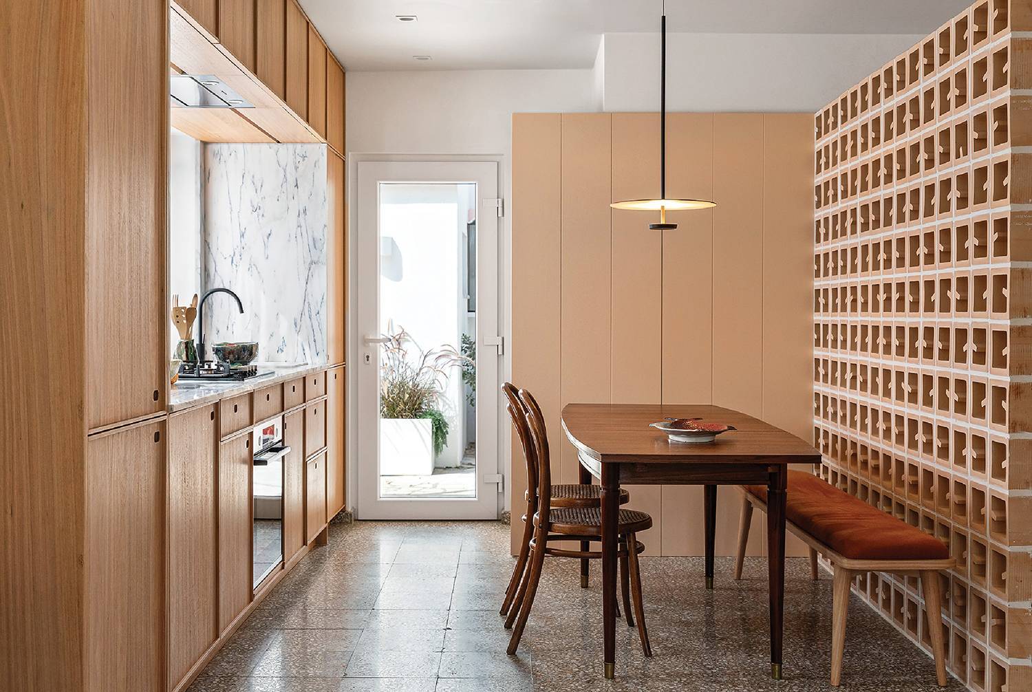 a dining table in a kitchen with wooden cabinets and divider