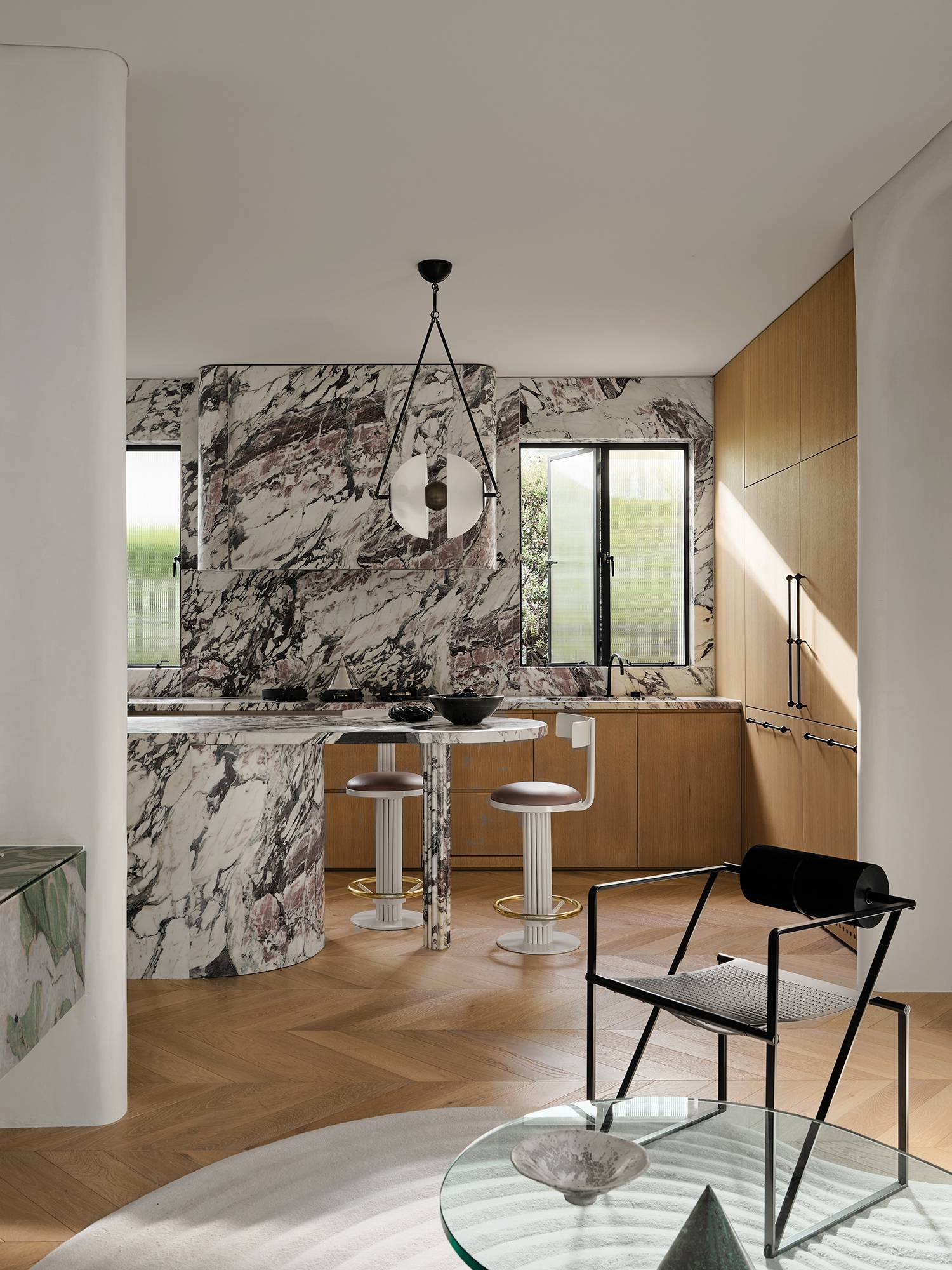 a modern kitchen with marble walls and wooden floors in home by Greg Natale