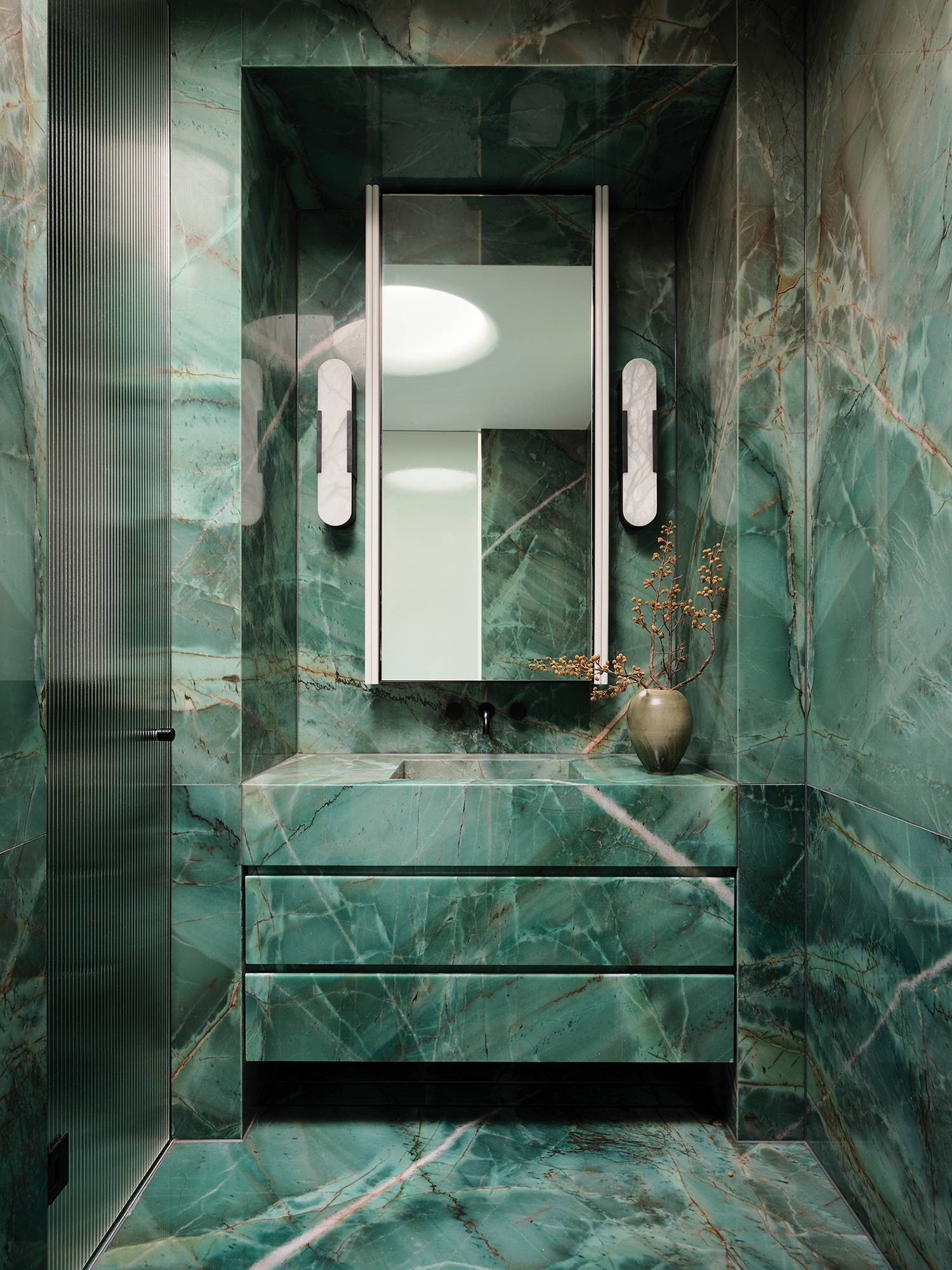 a bathroom with green marble walls and a mirror