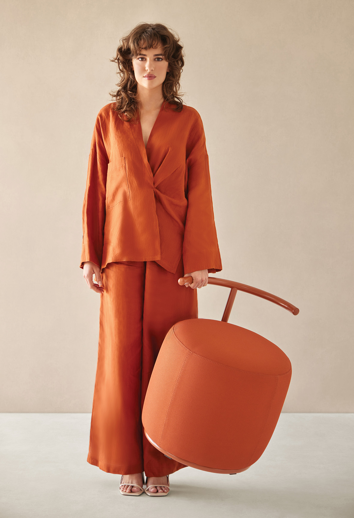 A woman in an orange suit holding a large orange suitcase