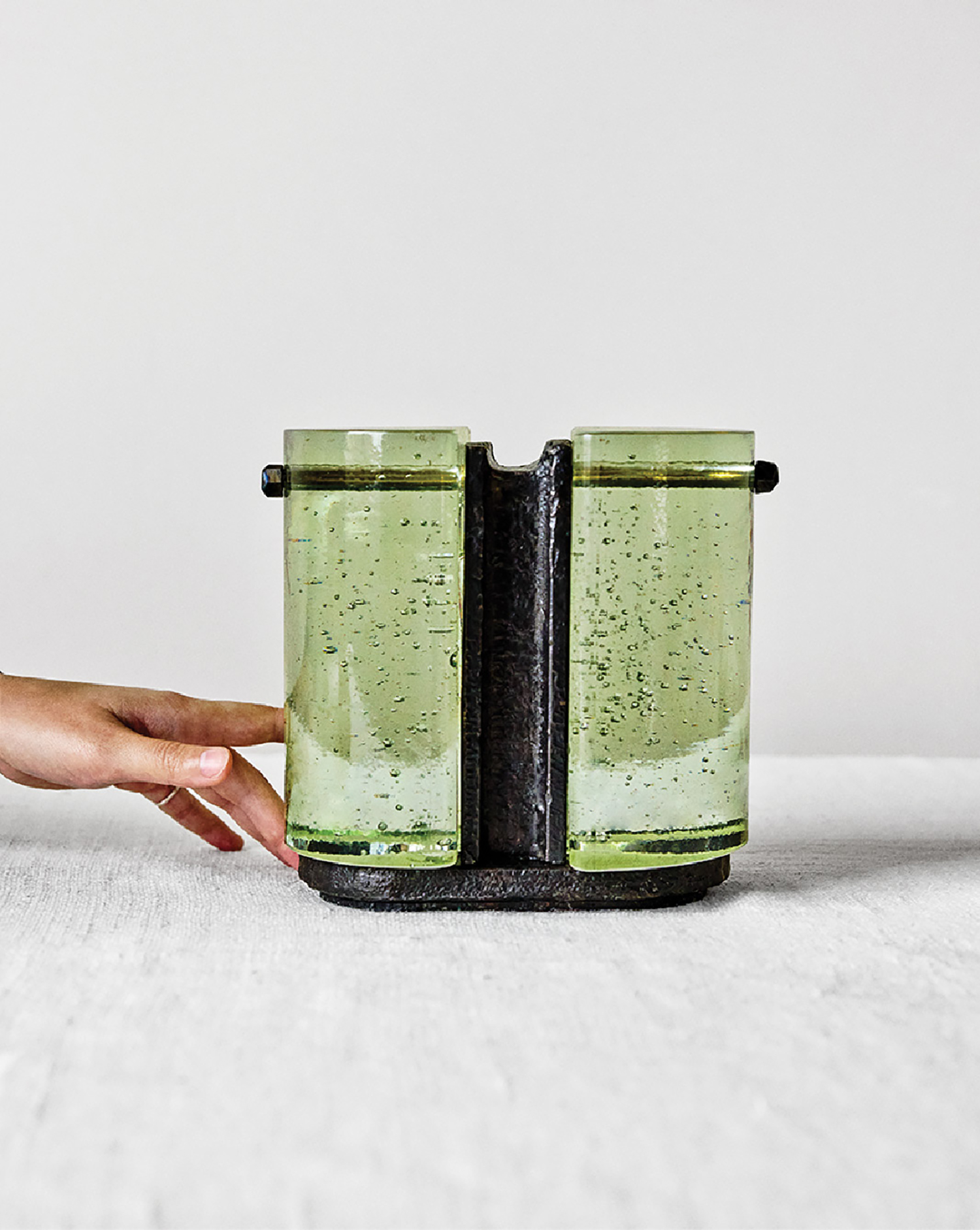 A person is holding a green glass container