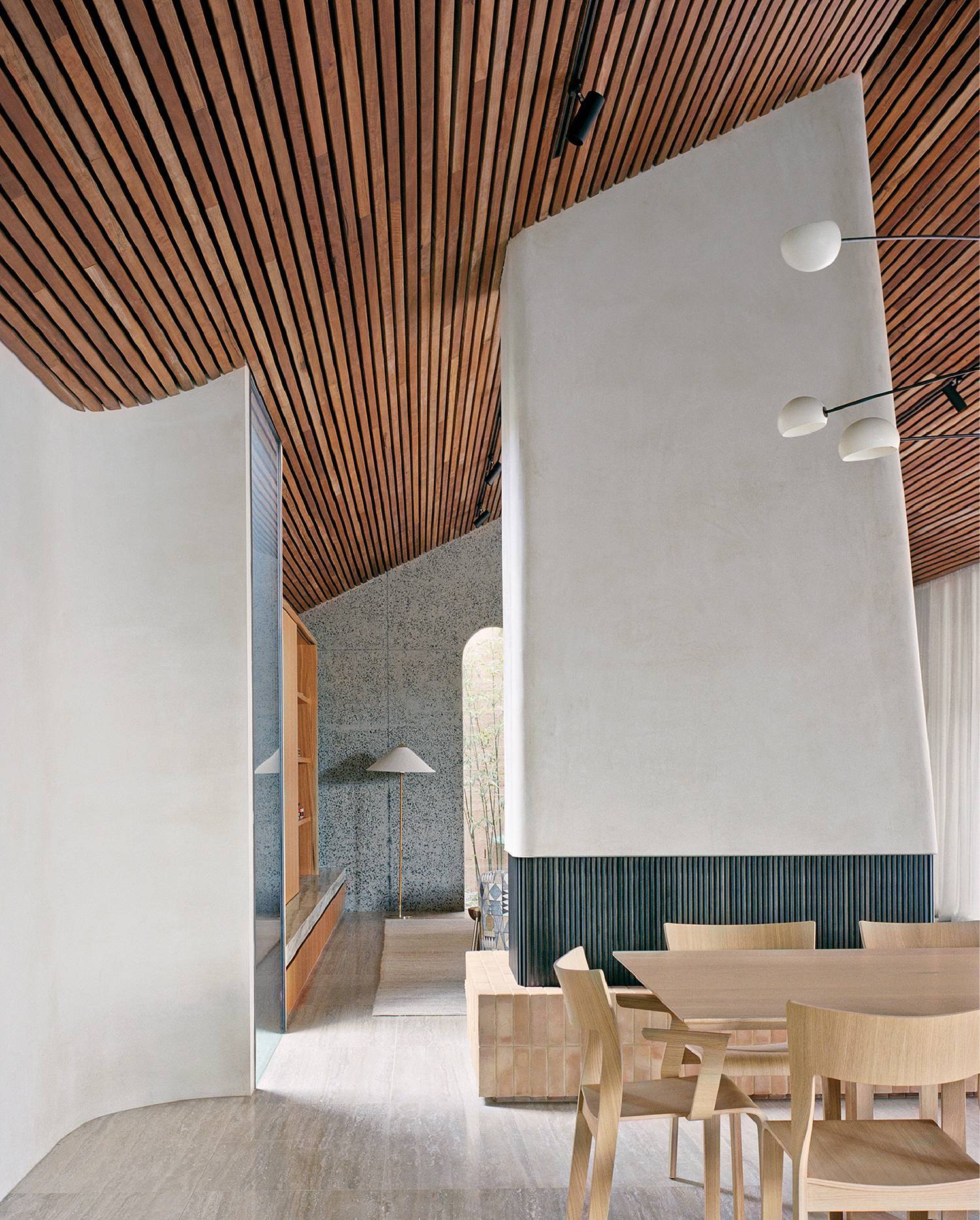 A dining room with wooden ceiling and white walls