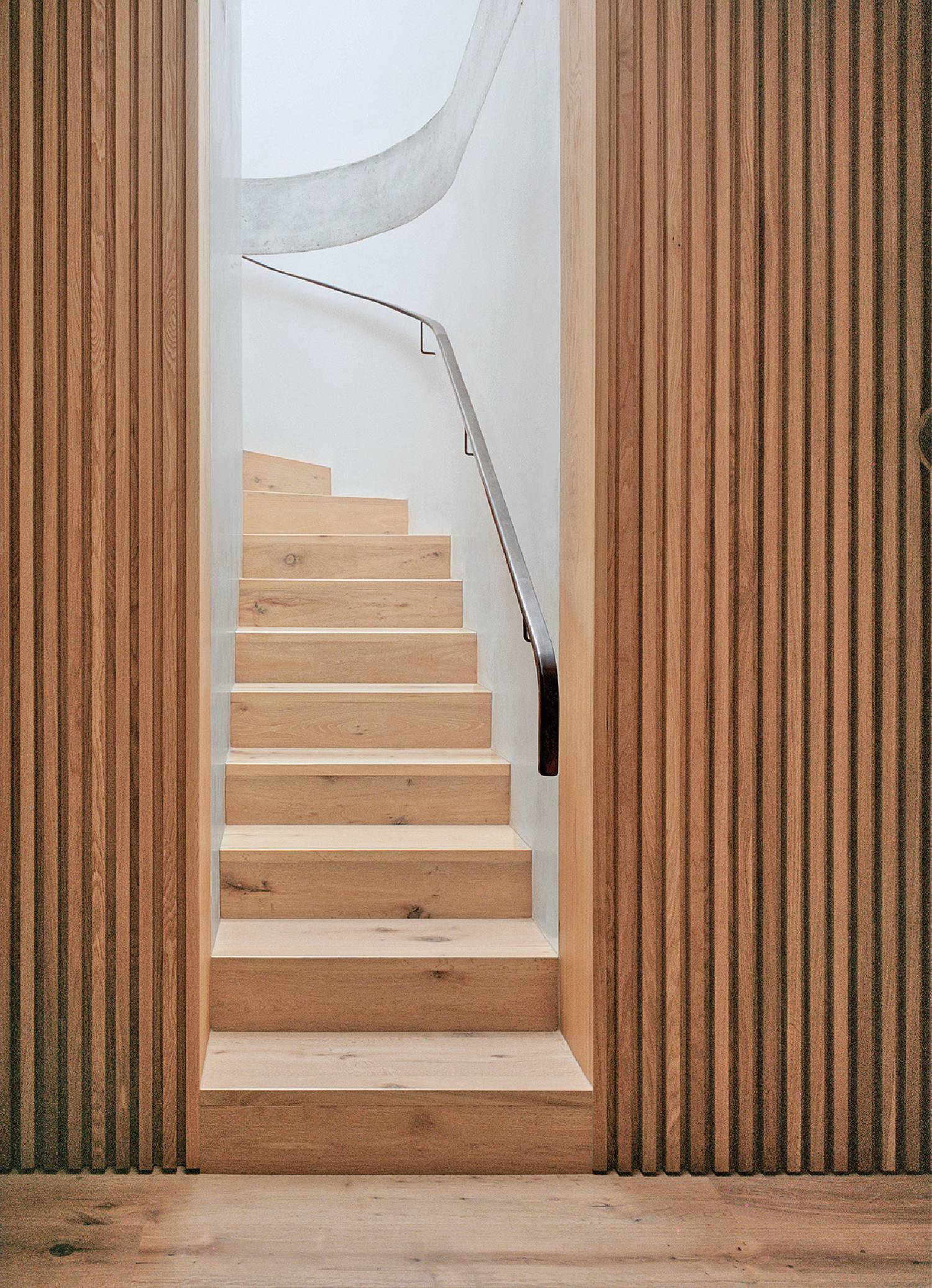 A wooden staircase leading to a white wall