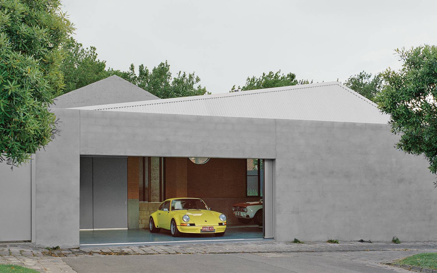 A yellow car parked in front of a concrete house