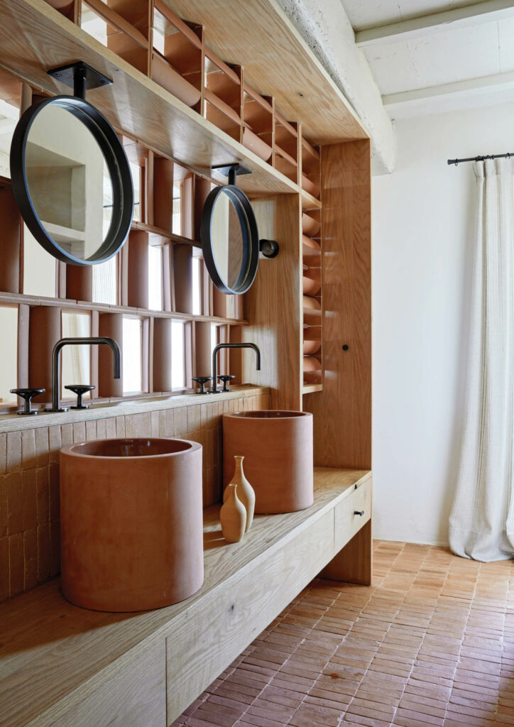 Also terra-cotta, raw and porous on the outside, sealed inside, a guest bathroom’s sinks are set within a custom pine vanity.