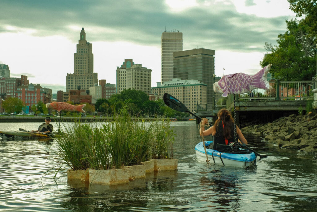 floating planters in a river near people in canoes