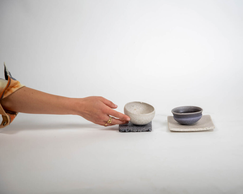 a hand reaching for sustainable bowls and tiles