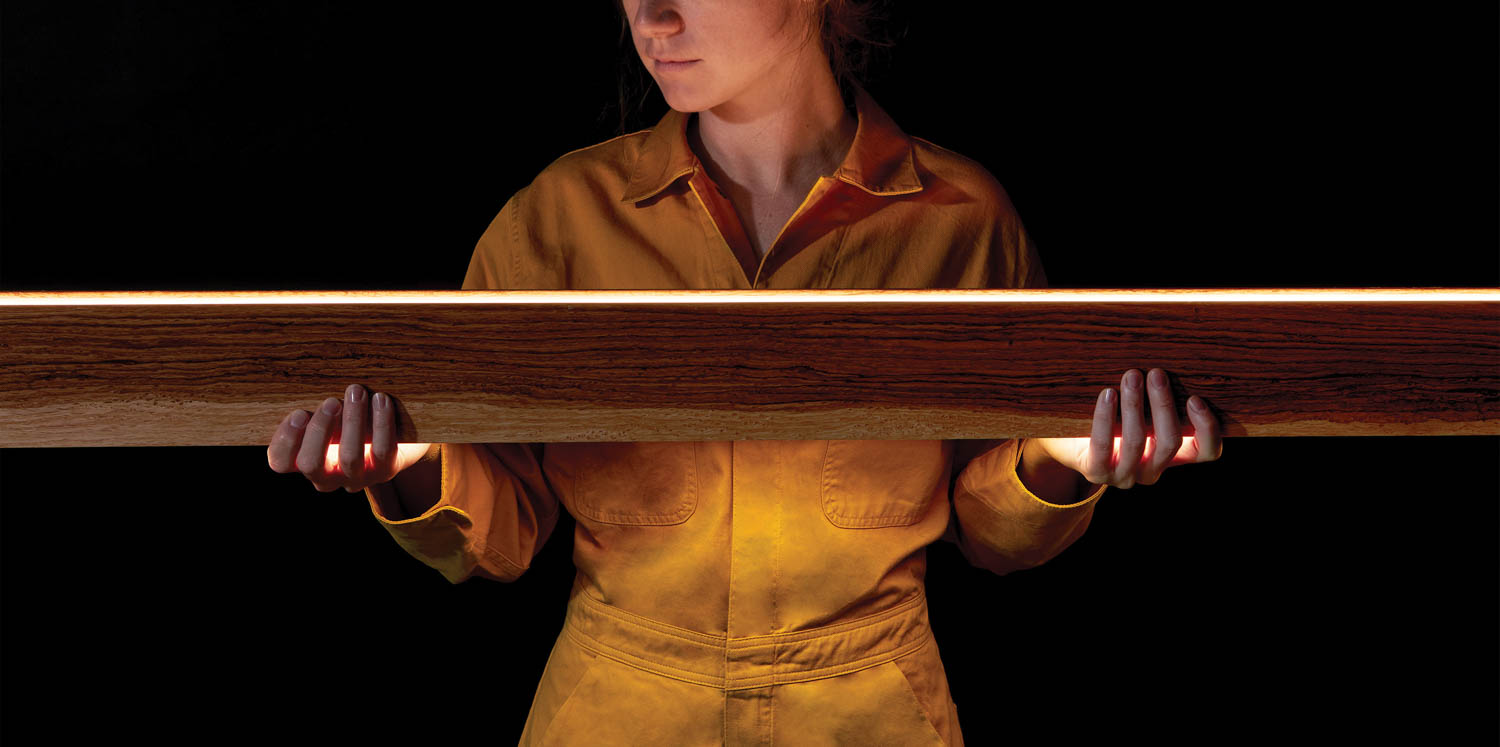 a person holding a beam of wood with an LED strip