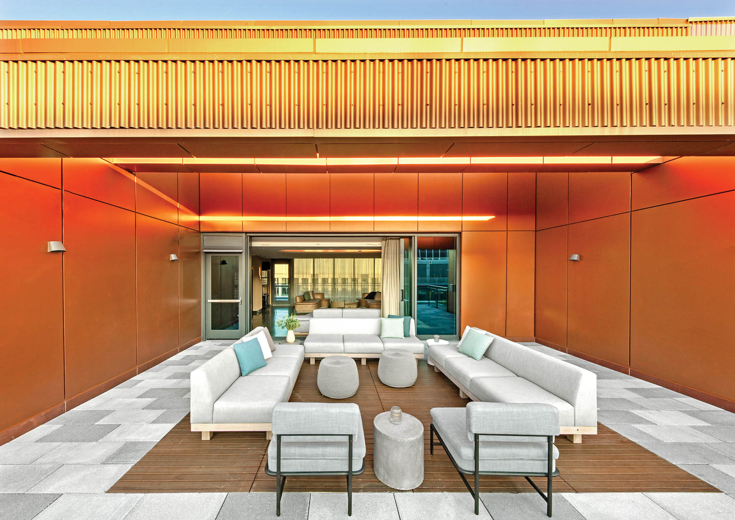 hotel rooftop bar with concrete seating and bright orange walls and lights