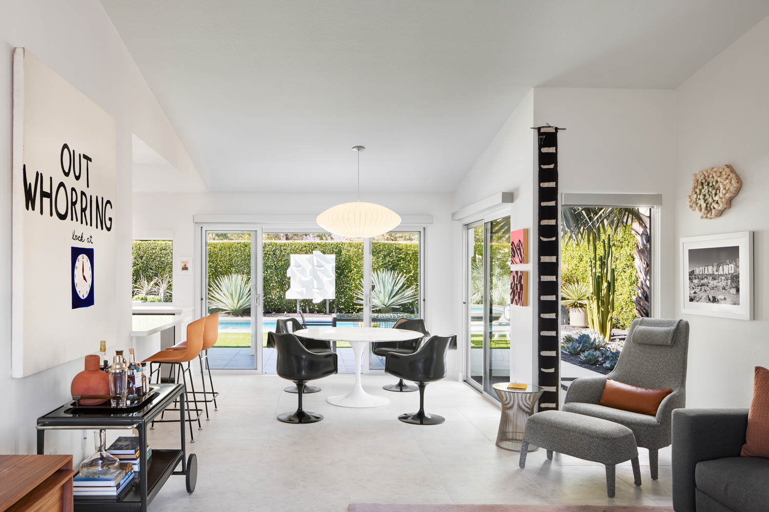 dining area with funky black chairs, seating area, bar cart and artwork