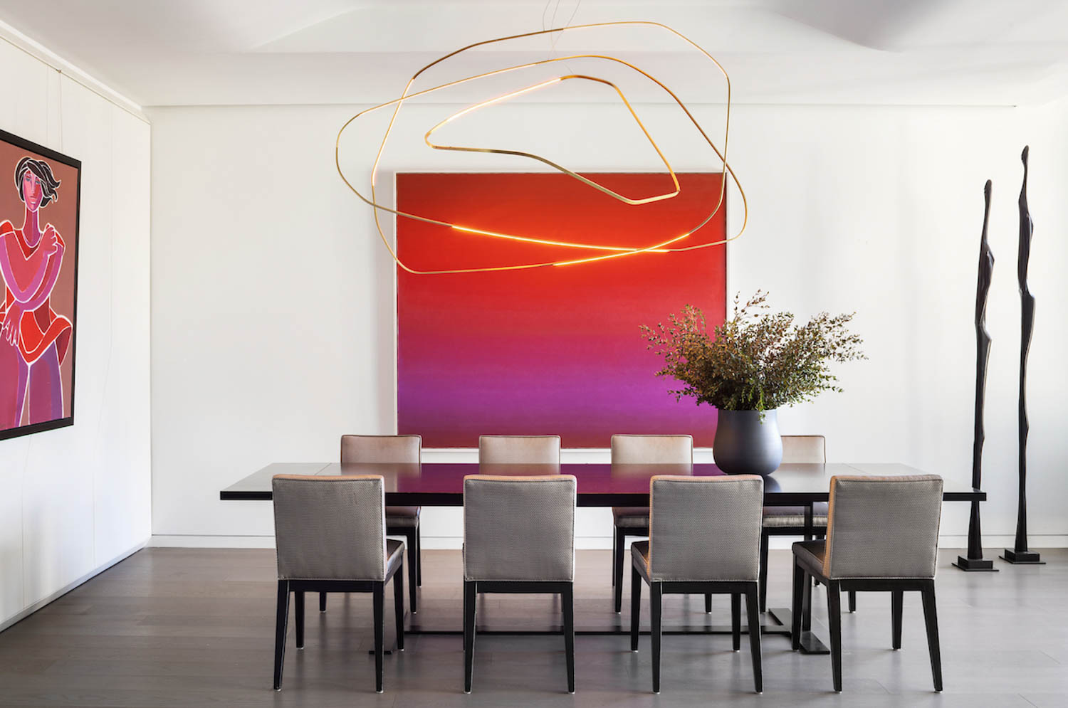 dining area with amorphous chandelier, bright red painting and long table