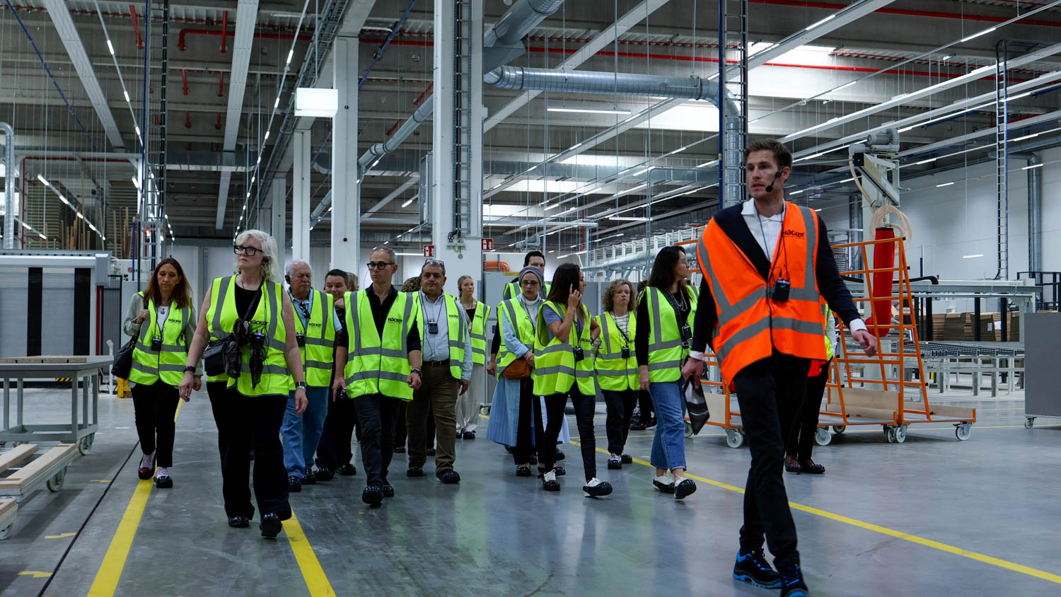 multiple people standing in factory space in bright green safety vests