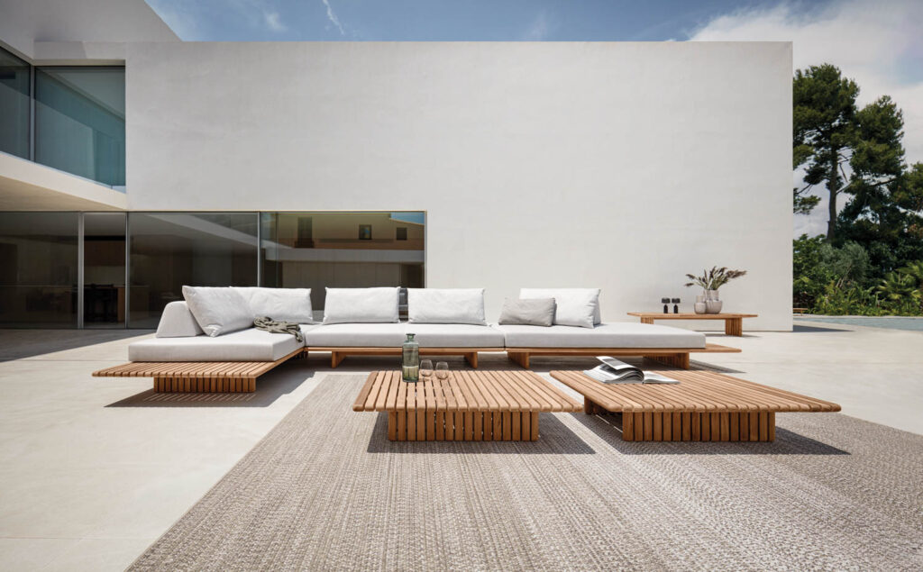 white couch, teak coffee table and other furnishings on an outdoor deck