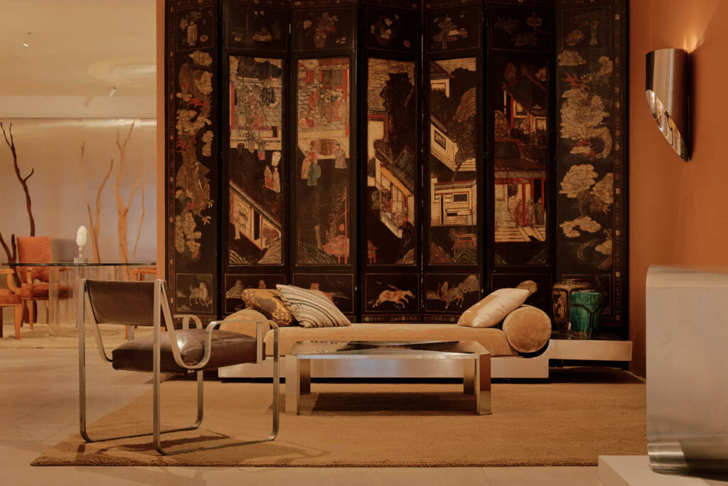 room with daybed, brown chair and silver table in front of divider