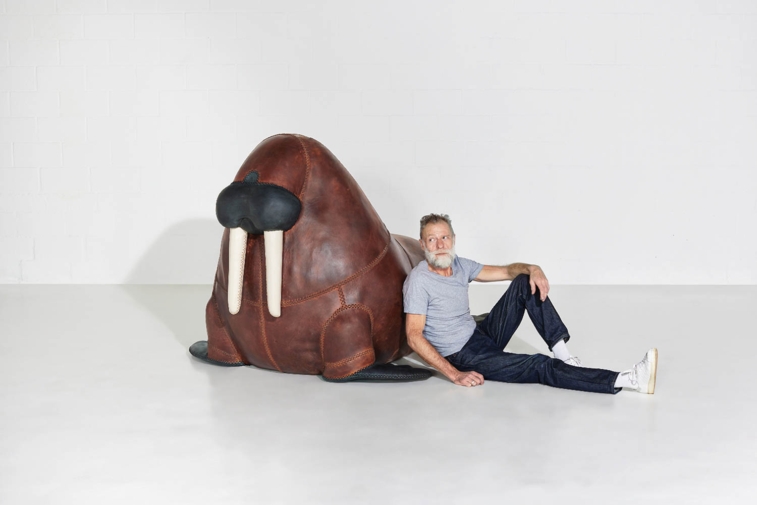 man sitting next to a large walrus statue