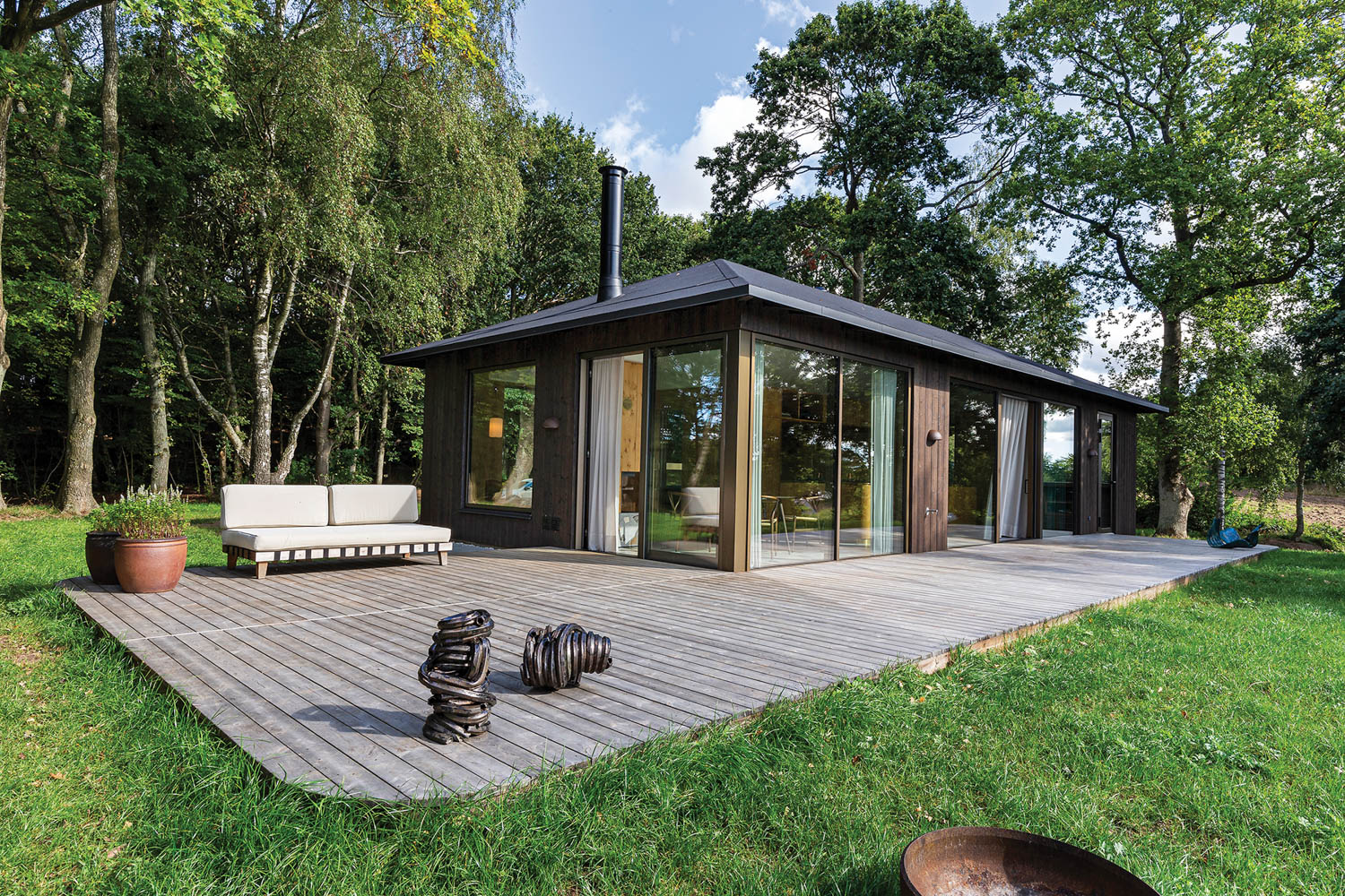 wooded home enclosed in glass next to a wooden deck