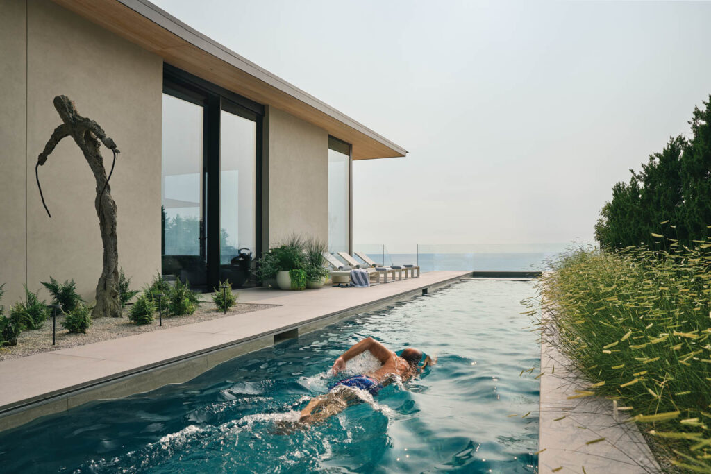 person swimming in a pool along the outskirts of a lake home