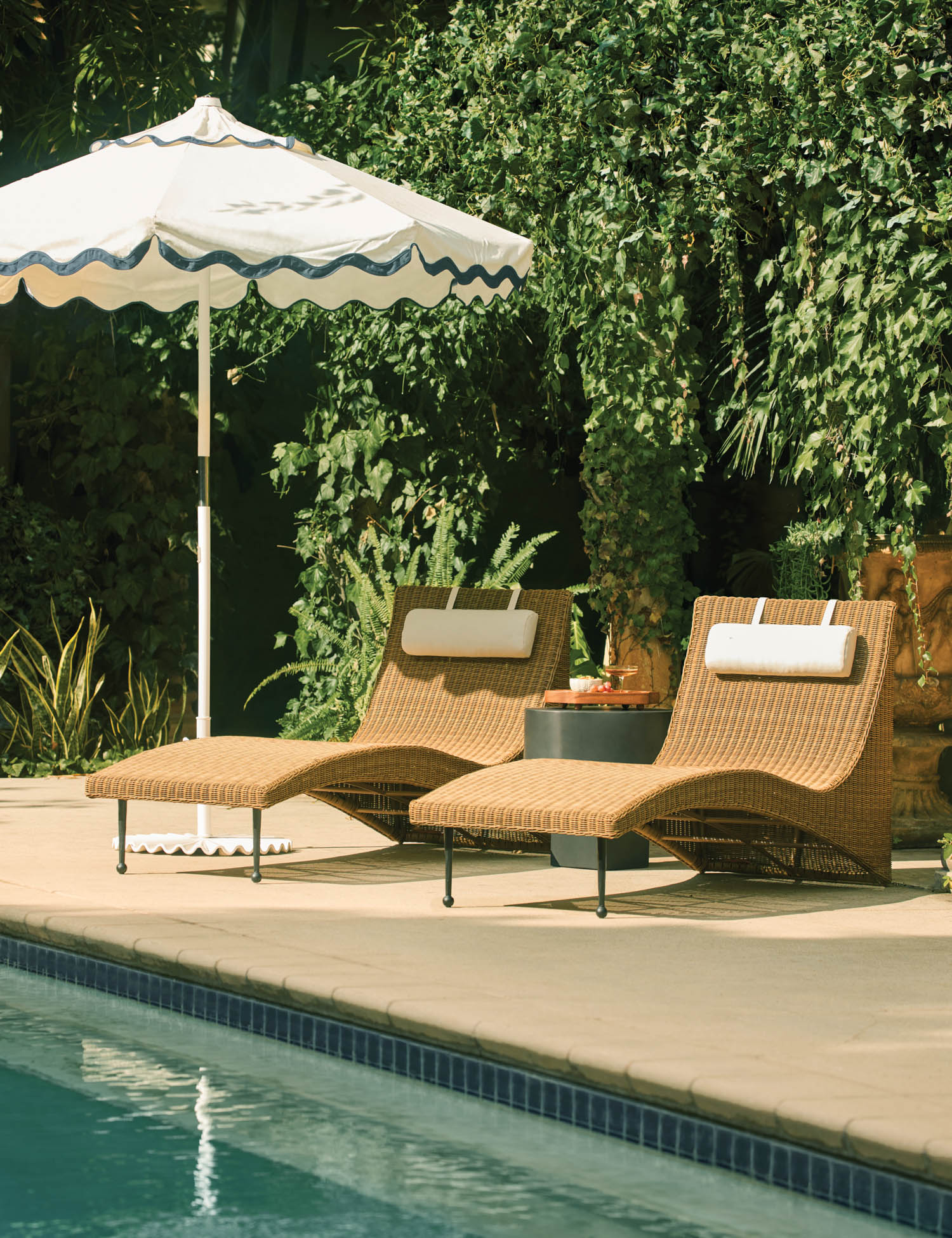 2 wicker sunchairs underneath a white umbrella with scalloped blue trim