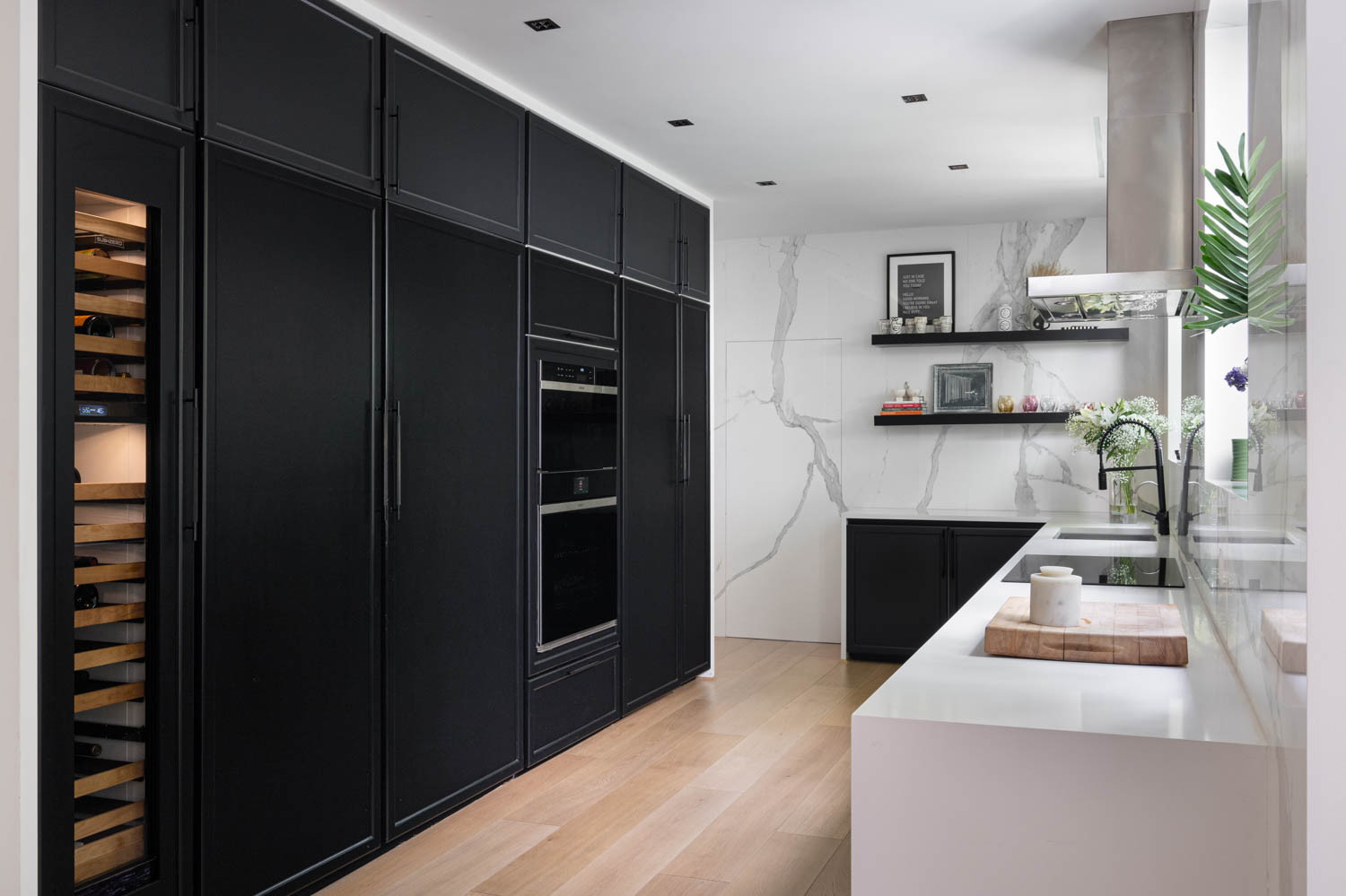 all black cabinetry in this kitchen with white marble walls and black shelving