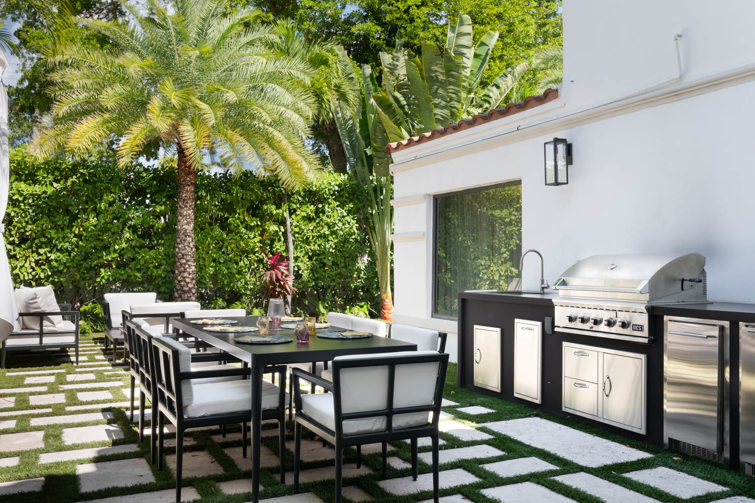 outdoor dining area with black and white themed chair and table and surrounding greenery