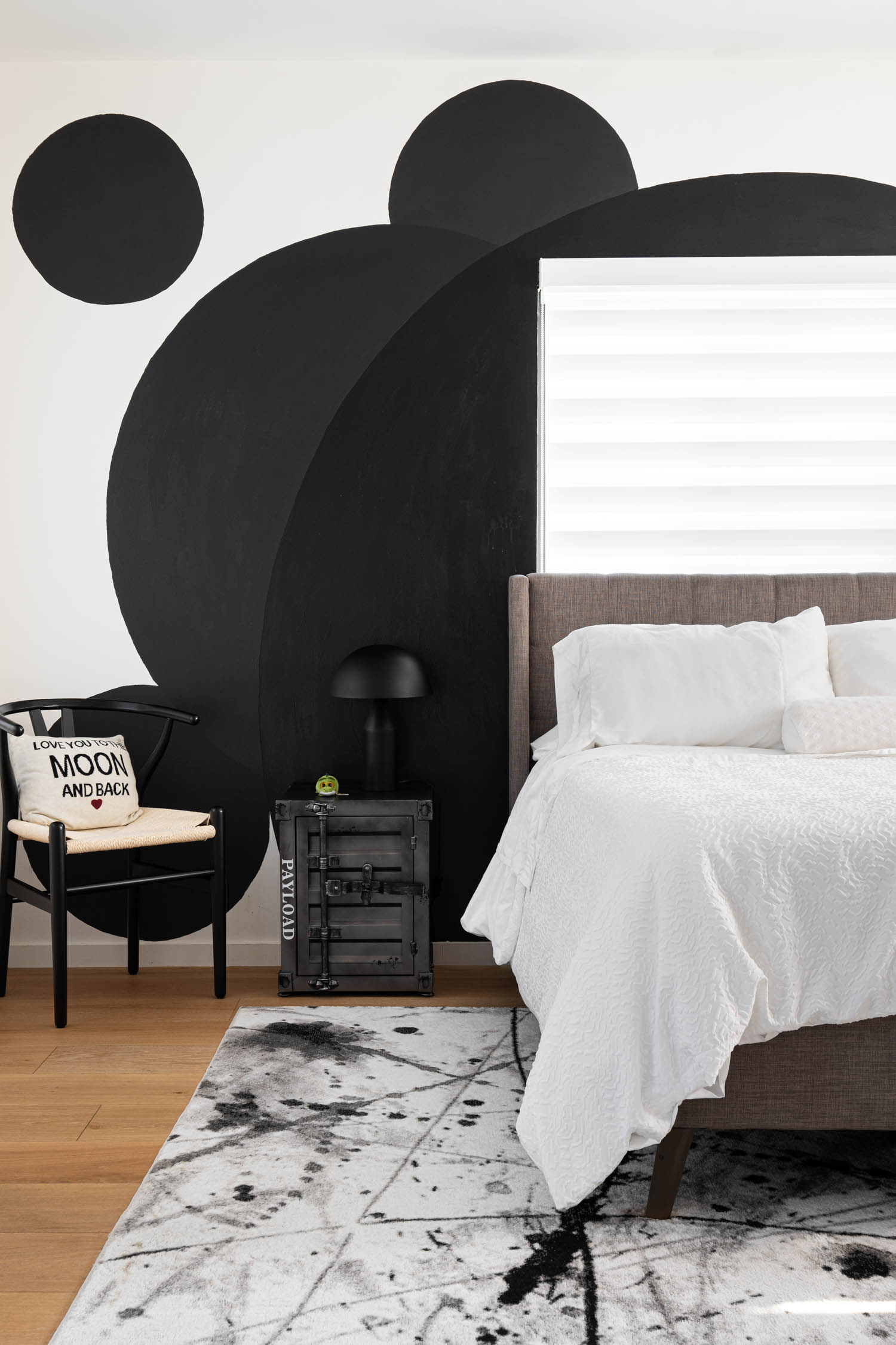 bedroom with white bed, marbled patterned floor and black dots on wall