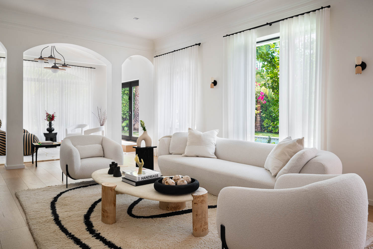 living room with white couches, wooden coffee table and white drapes