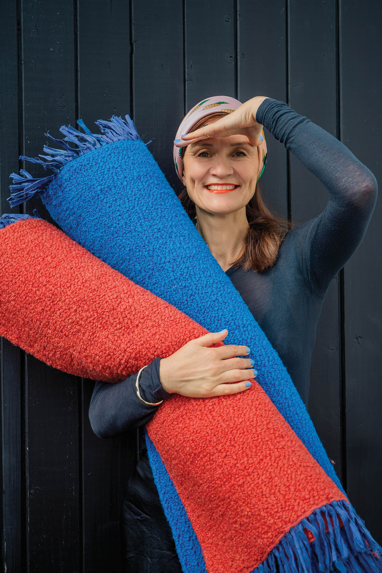 Jutta Werner holding blue and red rugs