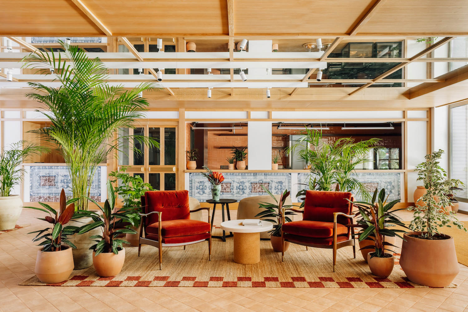 light-filled seating area with plants and red chairs