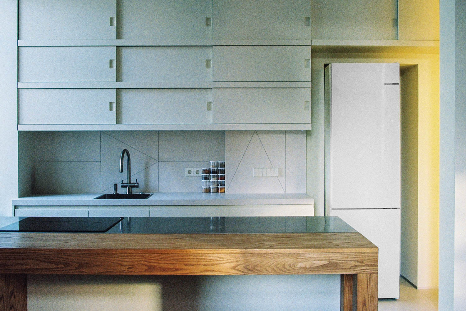 kitchen area with long wooden table and white cabinets