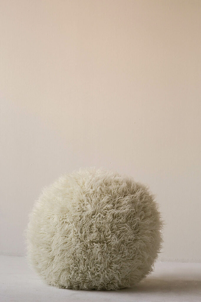 a fuzzy ottoman in cream