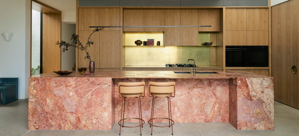 kitchen area with pink marble island and wooden cabinets