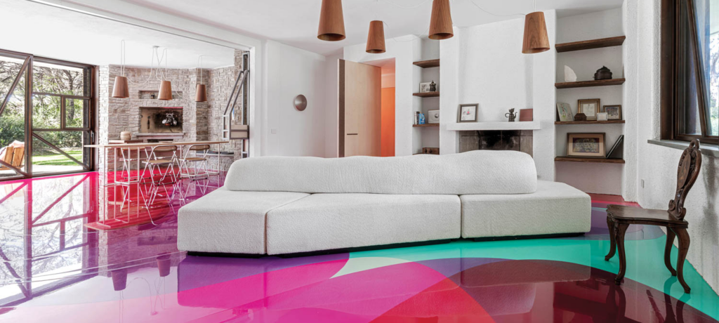 living area of Tuscan home with bright pink flooring and white couch